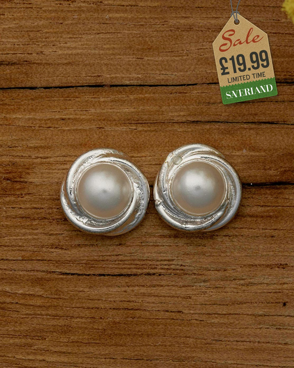 Silver swirl faux pearl round stud earrings on wooden background