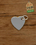 Polished silver heart charm pendant with jump ring on wooden background