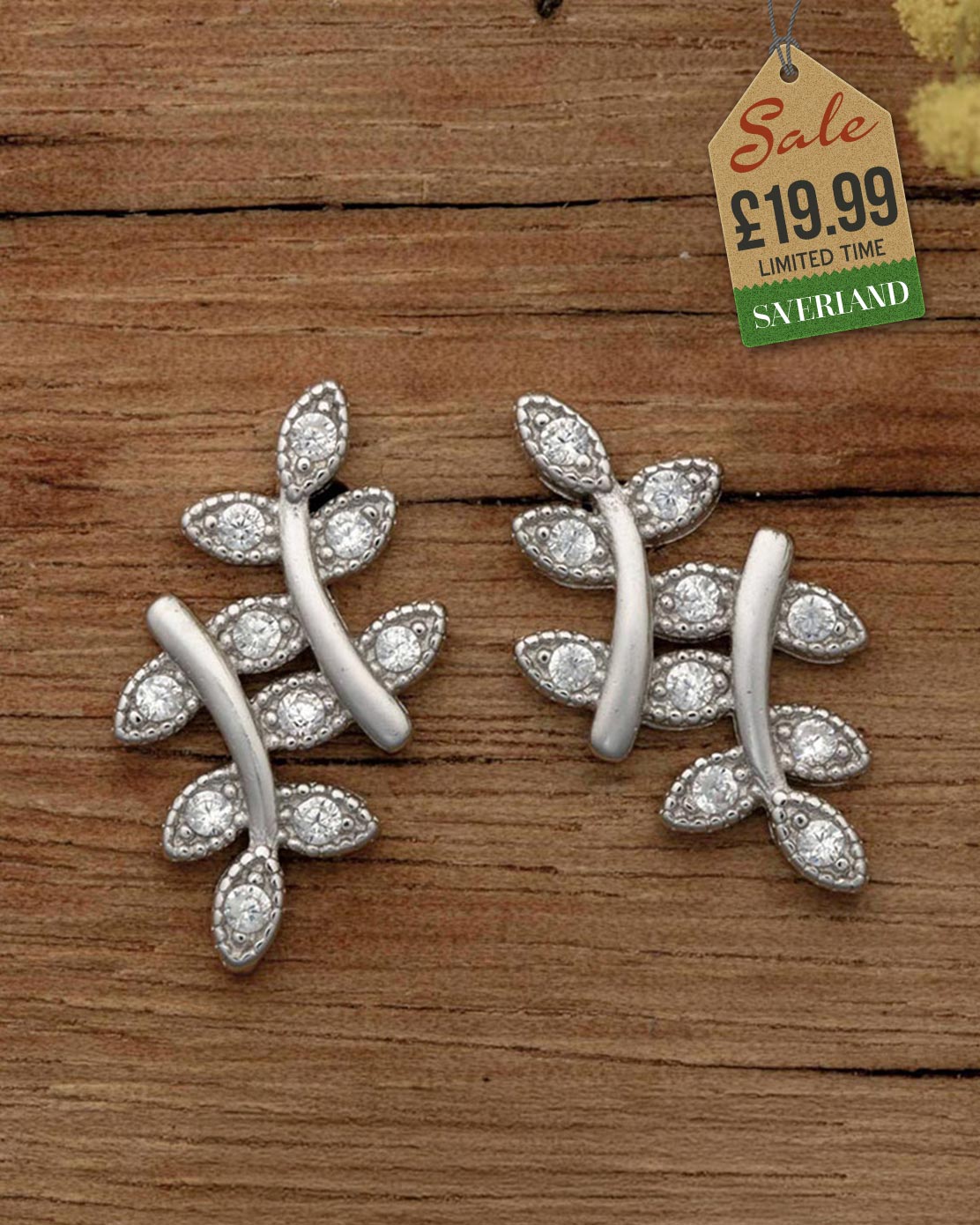 Silver leaf branch stud earrings with crystal cubic zirconia settings on rustic wood background