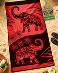 Deep Red and black mandala elephant jacquard beach towel laid flat on sand with beach accessories