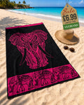 Hot Pink tribal elephant head beach towel laid on sand at tropical beach