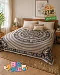 Black and cream elephant mandala tapestry bedspread draped over a double bed in a boho-style bedroom