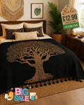 Black bed throw with gold tree of life design and black tassel trim draped over a double bed in a bohemian bedroom