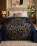 Navy blue throw blanket with gold ornate Hamsa hand and mandala design draped over a double bed