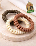 Three spiral hair ties in natural tones on marble