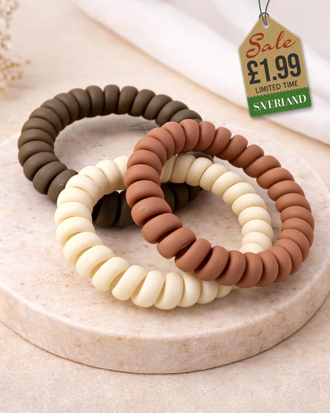Three spiral hair ties in natural tones on marble