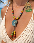 Ocean blue glazed ammonite shell pendant necklace with multicolour ceramic beads worn at tropical beach
