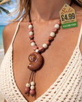 Earthy brown glazed nautilus shell pendant necklace with terracotta and cream ceramic beads worn at tropical beach