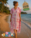 Woman wearing a pink and red tie-dye kaftan cover-up dress walking barefoot on a tropical beach