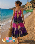 Woman wearing a tie-dye purple and pink maxi dress with gold shimmer detail on a sandy beach