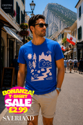 Man wearing a royal blue t-shirt with a blush pink nature scene graphic including mountains, trees, waves and flowers, photographed on Main Street Gibraltar