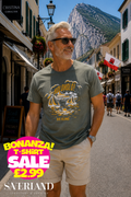 Man wearing an olive green t-shirt with a Holoholo Big Island sailboat graphic print, photographed on a Gibraltar street
