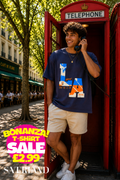 Man wearing a navy blue LA West Coast graphic t-shirt leaning against a red telephone box