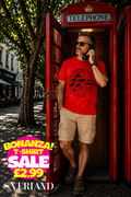 Man wearing a red t-shirt with black tribal fish and swirl graphic, standing in a classic red London telephone box