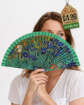 Folding hand fan with a print inspired by Irises by Vincent van Gogh with rich green frame held by woman