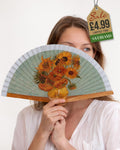 Folding hand fan with a print inspired by Sunflowers by Vincent van Gogh with sage green and grey frame held by woman